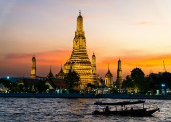 Two boats floating on the water in front of a tall building